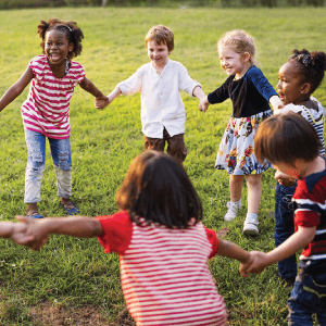 Picture containing children holding hands and laughing.