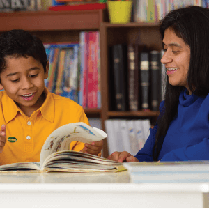 Student and teacher viewing a book together.